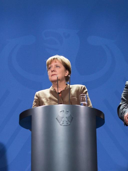 Bundeskanzlerin Angela Merkel, CSU-Chef Horst Seehofer und SPD-Chef Sigmar Gabriel stehen bei einer gemeinsamen Pressekonferenz in Berlin hinter Rednerpulten.