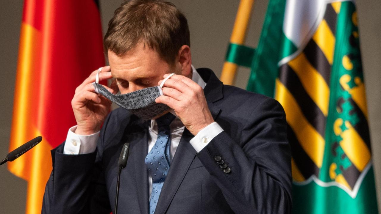 Sachsens Ministerpräsident Michael Kretschmer (CDU) zieht nach seiner Rede in einer Sondersitzung des Sächsischen Landtages seinen Mundschutz an.