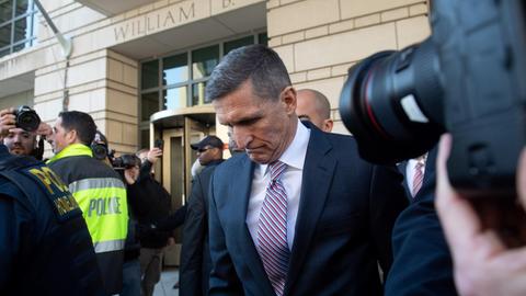 Der ehemalige Nationale Sicherheitsberater der USA, Michael Flynn, verlässt mit geneigtem Kopf ein Bundesregricht in Washington D.C. Er wird von Polizisten begleittet und mehrere Fotografen machen Fotos.