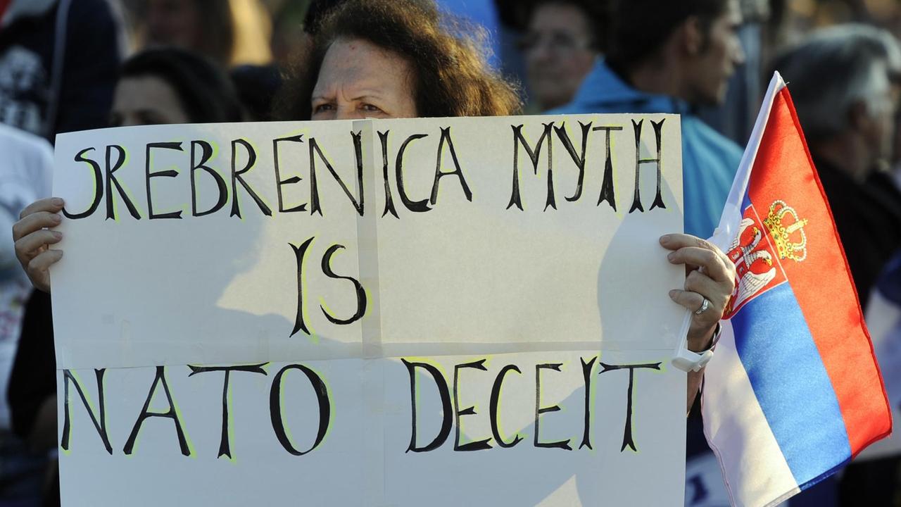 Demonstrantin hält ein Transparent mit der Aufschrift, der Mythos Srebrenica sei eine Lüge der Nato