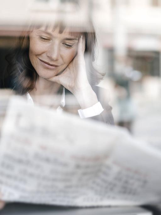 Frau liest Zeitung in einem Café