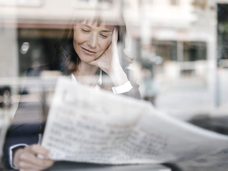 Frau liest Zeitung in einem Café