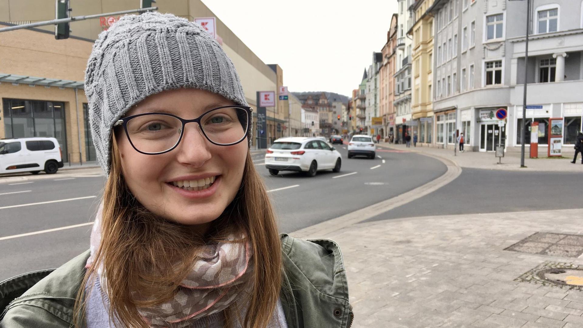 Die 28-jährige Anne Häring ist seit März die erste Klimaschutzmanagerin in der Stadtverwaltung von Eisenach - ihre Heimatstadt. Dort steht sie in einer Straße und lächelt in die Kamera.