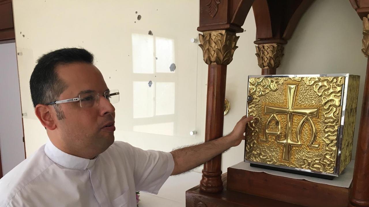 Pater Raul zeigt die Einschüsse im Tabernakel der Kirche Kirche La Divina Misericordia, Nicaragua