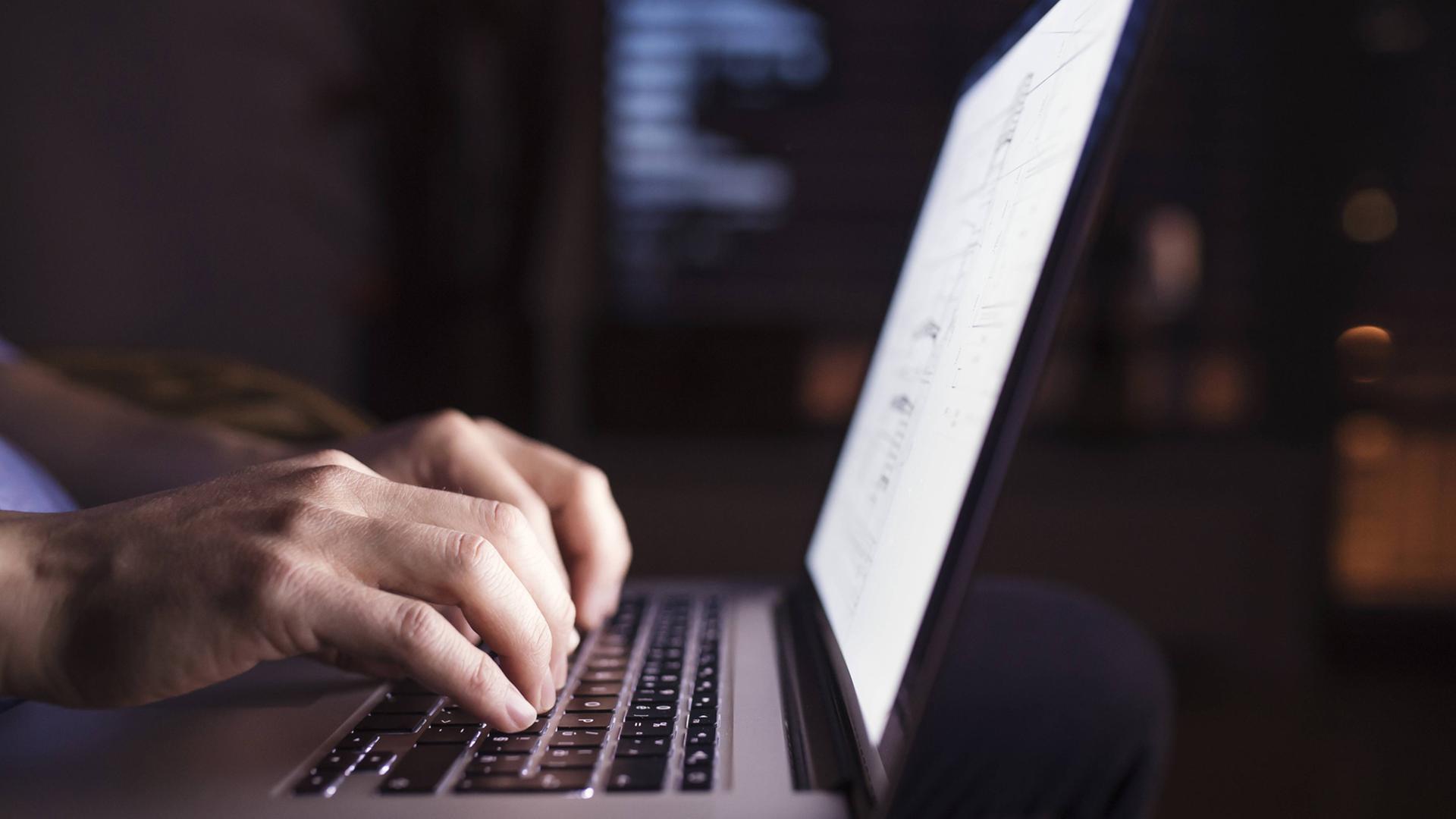Mann tippt bei Dunkelheit am Computer
