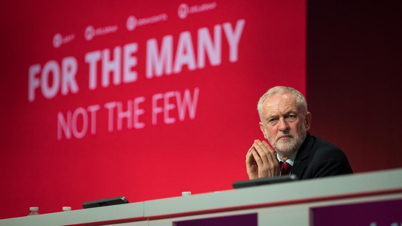 Der Vorsitzende der britischen Labour Party, Jeremy Corbyn, sitzt am 25.09.2017 in Brighton (Großbritannien) anlässlich des Labour-Parteitages vor einem Bildschirm mit der Aufschrift "For the many. Not the few". Vom 24.-27.09. kommen die Labour-Parteimitglieder zum Parteitag zusammen. 