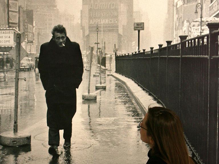 Eine Frau blickt auf ein Schwarz-Weiß-Bild mit James Dean, der den Times Square entlang geht.