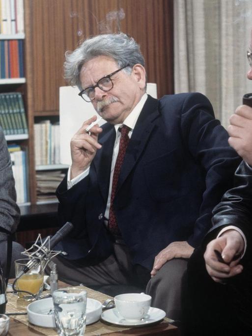 Die Autoren Lars Gustafsson, Elias Canetti und Uwe Johnson (von links) sitzen im Halbkreis um einen Tisch und diskutieren.