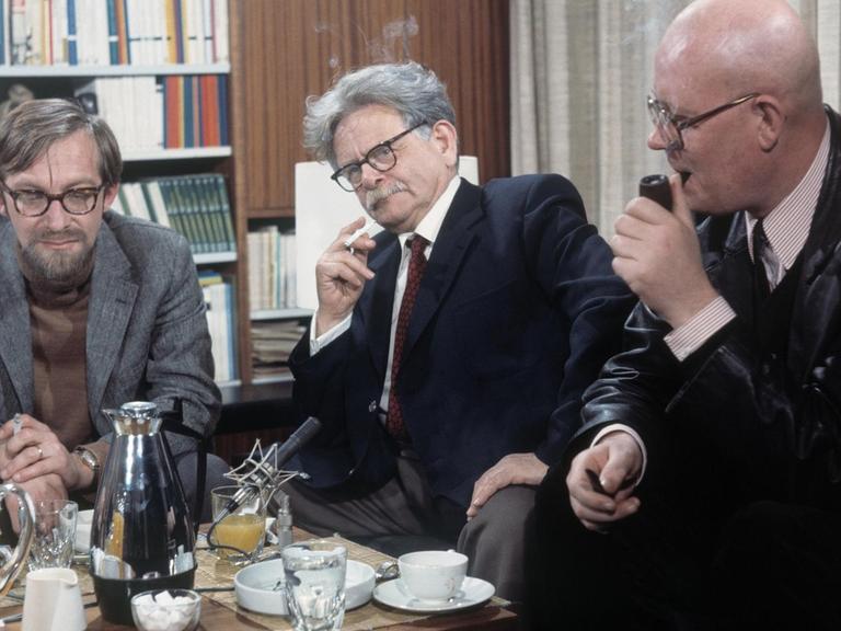 Die Autoren Lars Gustafsson, Elias Canetti und Uwe Johnson (von links) sitzen im Halbkreis um einen Tisch und diskutieren.