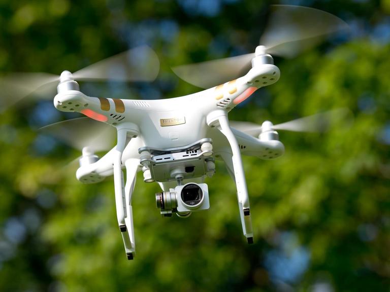 Eine ferngesteuerte Drohne mit einer Kamera schwebt in der Luft.