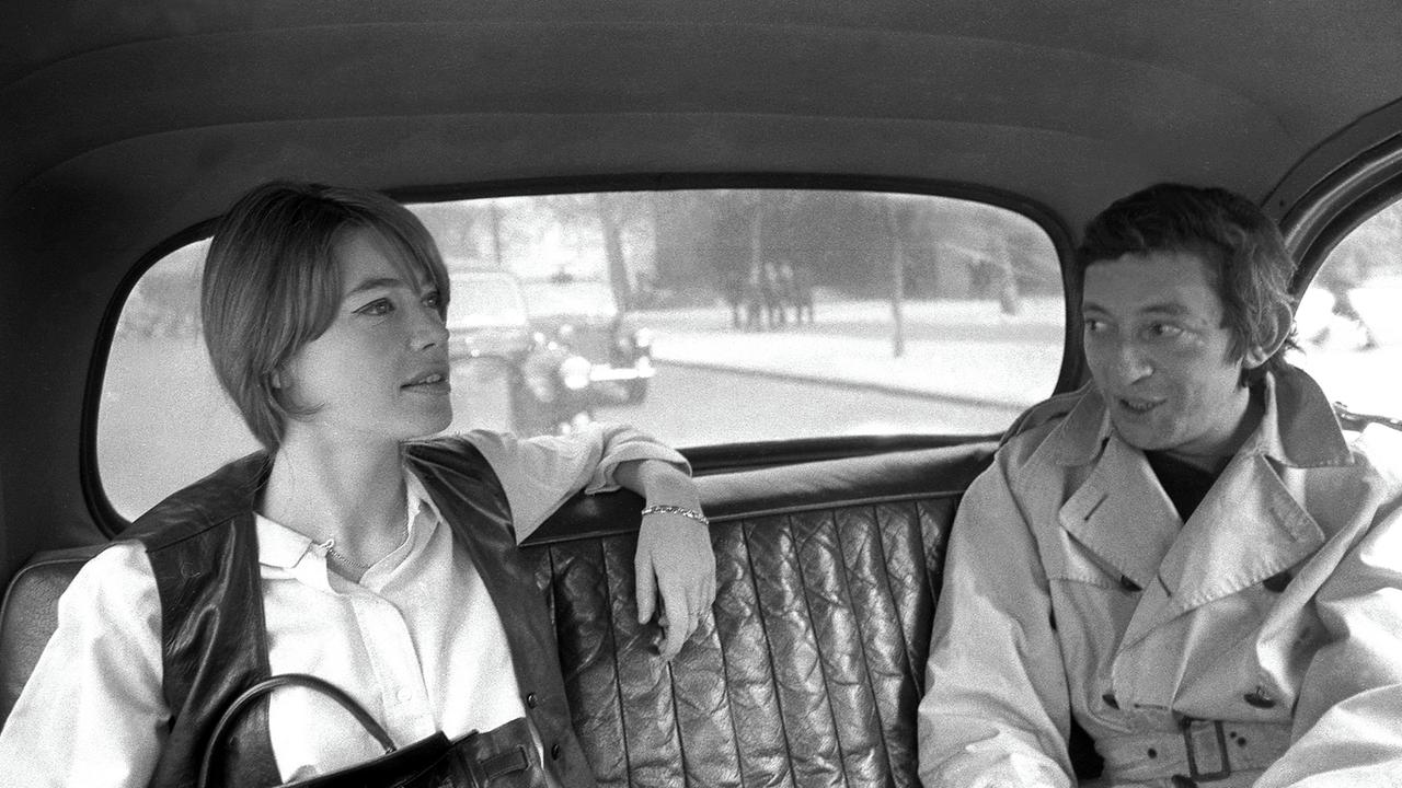 Ein Schwarz-Weiß-Foto zeigt Françoise Hardy, die im Jahr 1969 neben Serge Gainsbourg auf der Rücksitzbank eines Autos sitzt.