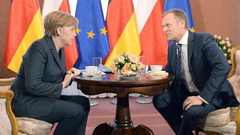 Bundeskanzlerin Angela Merkel (CDU) und der polnische Ministerpräsident Donald Tusk sitzen sich an einem gedeckten, runden Tisch gegenüber und beraten über die Krim-Krise.