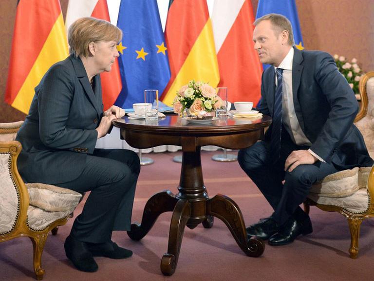 Bundeskanzlerin Angela Merkel (CDU) und der polnische Ministerpräsident Donald Tusk sitzen sich an einem gedeckten, runden Tisch gegenüber und beraten über die Krim-Krise.