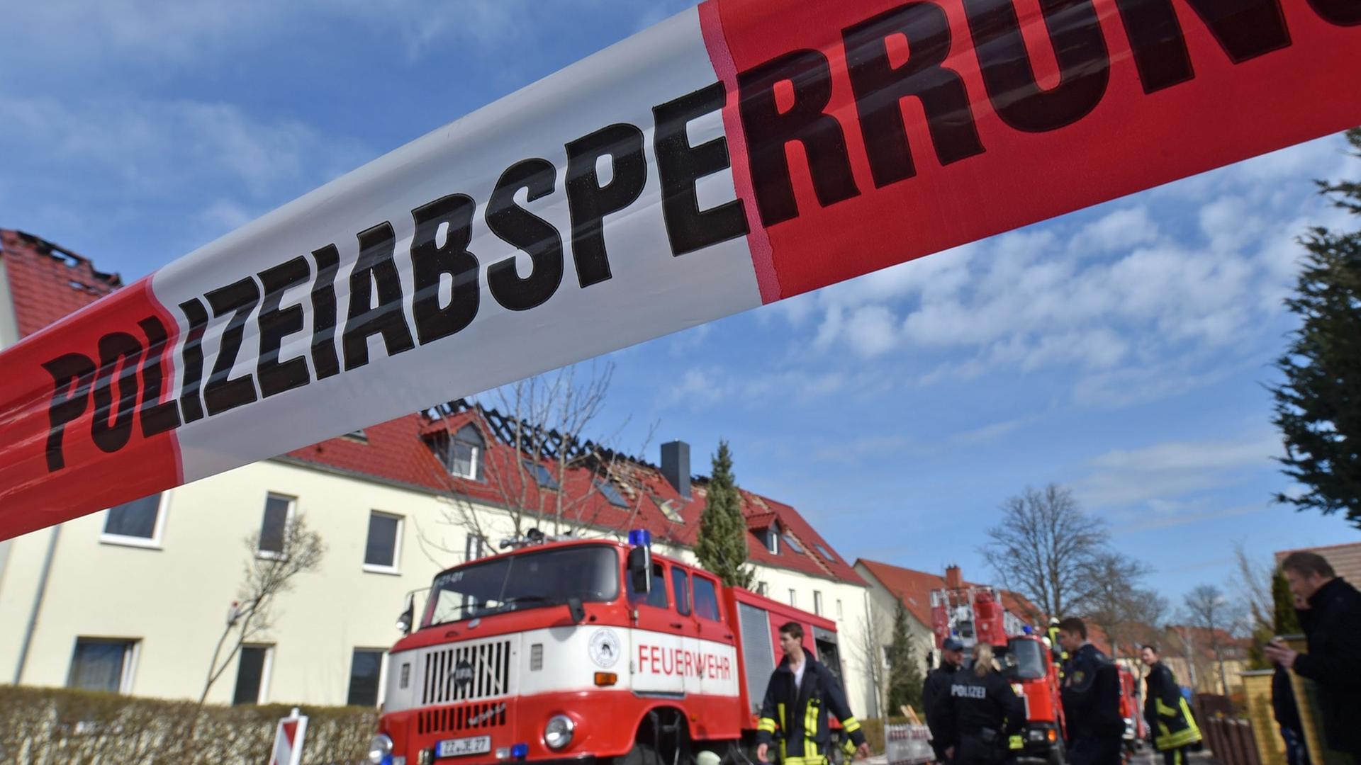 Einsatzkräfte von Feuerwehr und Polizei stehen am 04.04.2015 vor der zukünftigen Unterkunft für Asylbewerber in Tröglitz (Sachsen-Anhalt). In der Nacht hatte es in dem Gebäude gebrannt. Die Polizei ermittelt wegen Verdacht auf Brandstiftung.