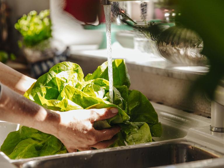 Eine Frau wäscht einen Salatkopf.