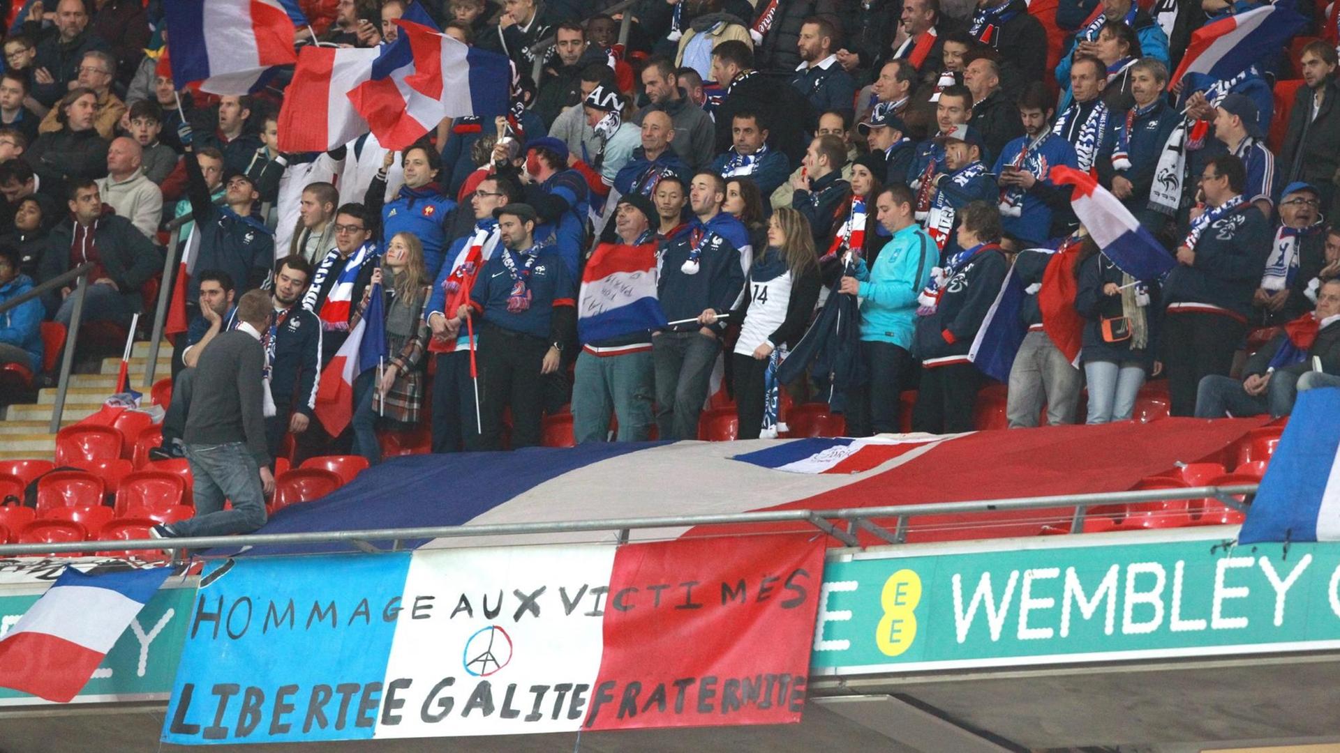 Zuschauer im Londoner Wembley-Stadion hinter einem Transparent mit der Aufschrift "Liberté-Egalité-Fraternité"
