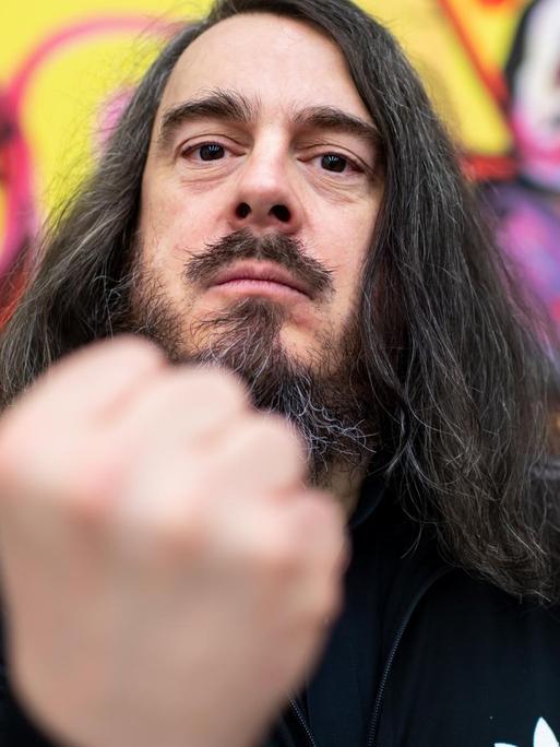 Jonathan Meese hält die geballte Faust in die Kamera. Jonathan Meese hält die geballte Faust in die Kamera.
