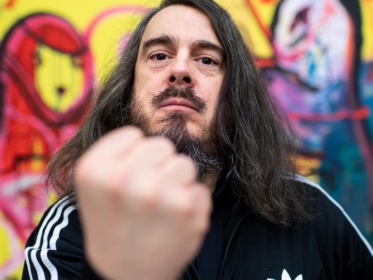 Jonathan Meese hält die geballte Faust in die Kamera. Jonathan Meese hält die geballte Faust in die Kamera.