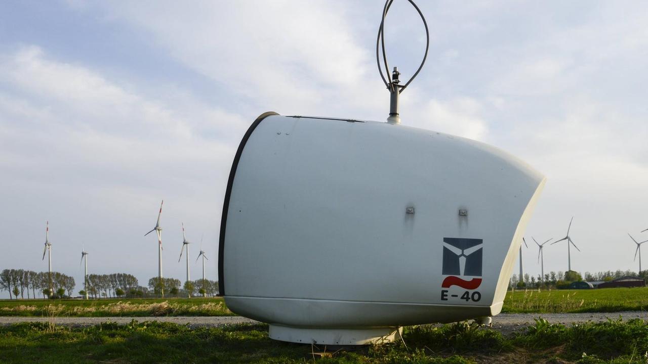 Eine kleine E-40 Windturbine liegt auf einer Fläche, im Hintergrund sind zahlreiche Windräder zu sehen.