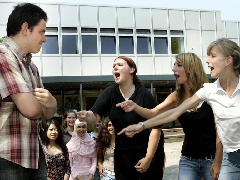 Schülerinnen der Liebig-Schule in Frankfurt am Main beschimpfen in einer gespielten Szene lautstark einen "Agressor" (l).