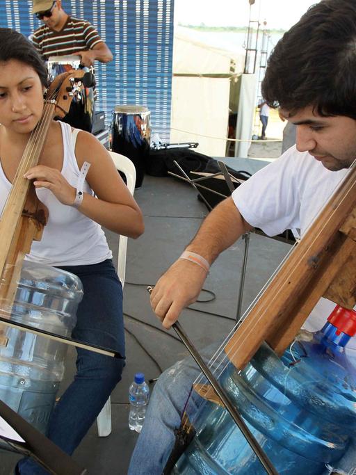 Mitglieder eines der paraguayanischen H2O-Orchesters spielen auf aus Wasserkanistern hergestellten Streichinstrumenten.