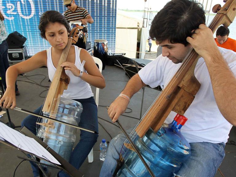Mitglieder eines der paraguayanischen H2O-Orchesters spielen auf aus Wasserkanistern hergestellten Streichinstrumenten.