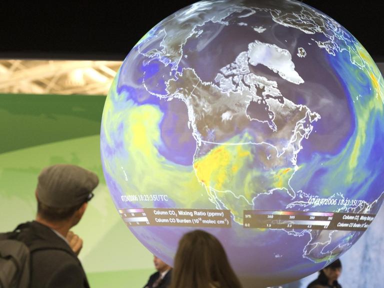 Menschen sehen sich den Globus bei der Klimakonferenz in Paris an.