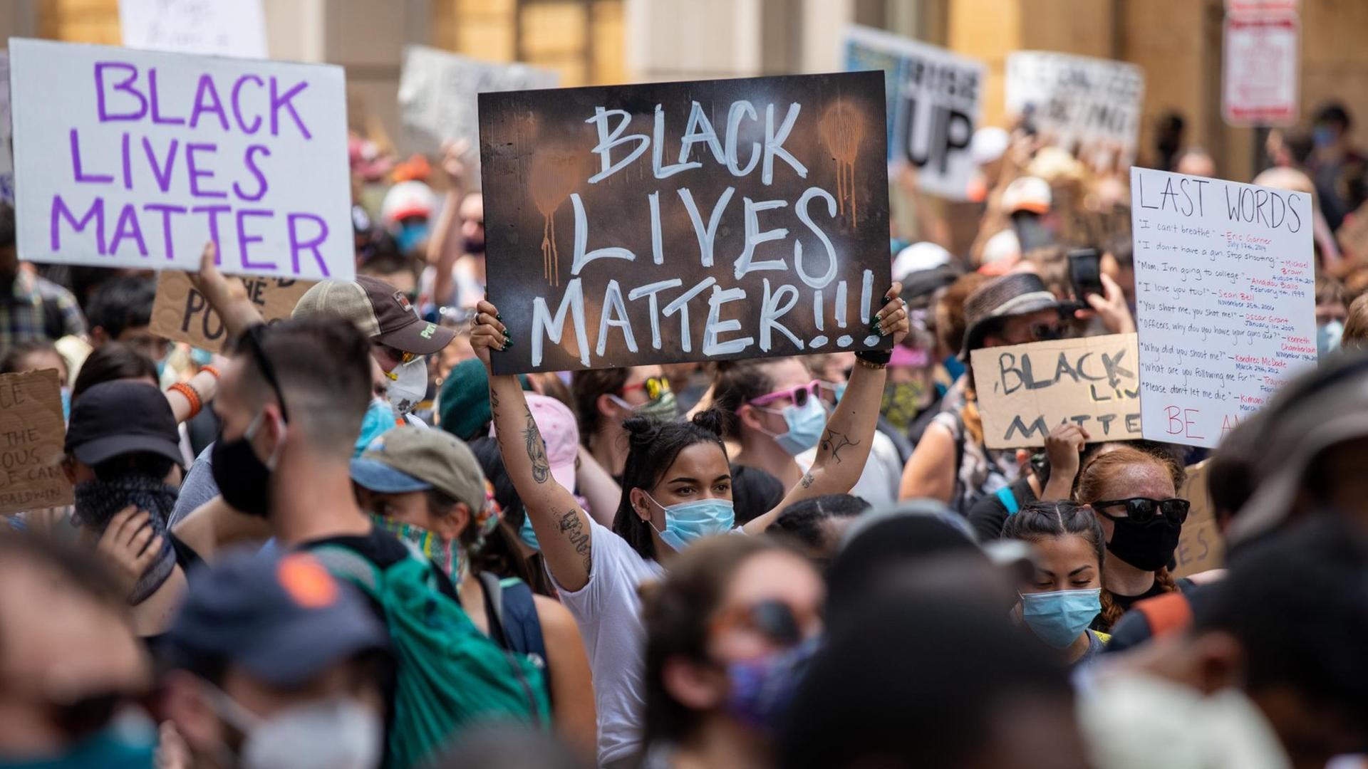 Protestierende halten Plakate mit der Aufschrift "Black Lives Matter" in die Höhe.