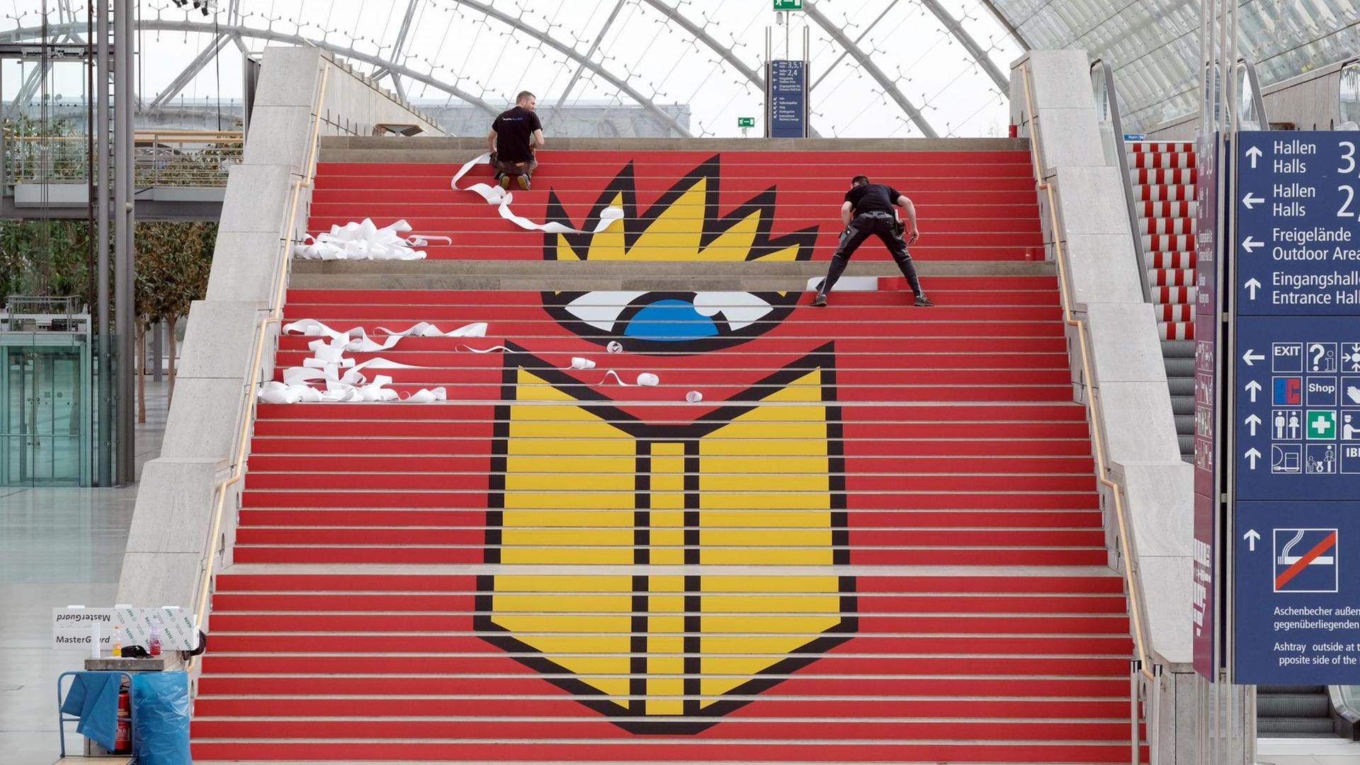 Ein Messebauer klebt am 14.03.2017 in Leipzig (Sachsen) das Logo der Leipziger Buchmesse auf eine Treppe in der Glashalle der Leipziger Messe. Vom 23. bis 26. März 2017 findet die Leipziger Buchmesse statt.