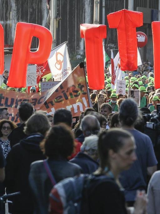 Menschen ziehen durch die Brüsseler Innenstadt. Einige von ihnen halten große Buchstaben in die Höhe, die die Forderung ergeben: Stop TTIP.