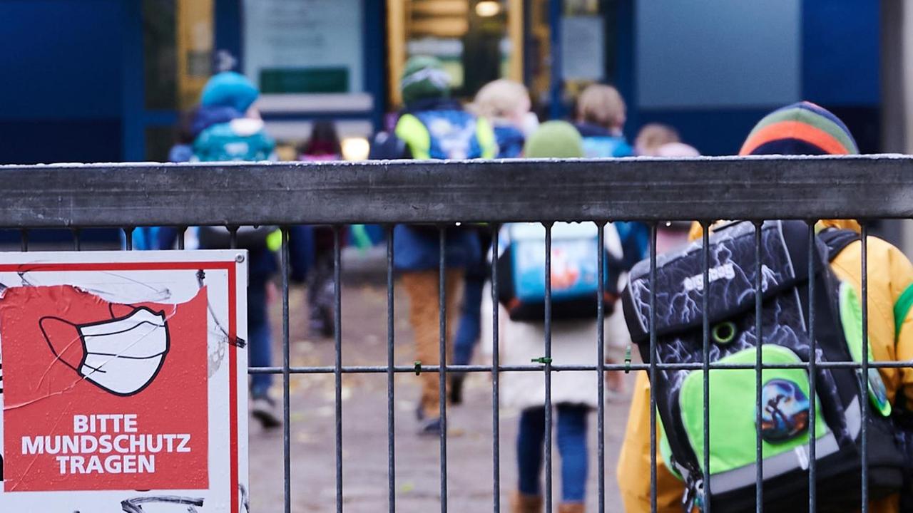 "Bitte Mundschutz tragen" steht am Eingang zu einer Grundschule in Berlin-Friedrichshain
