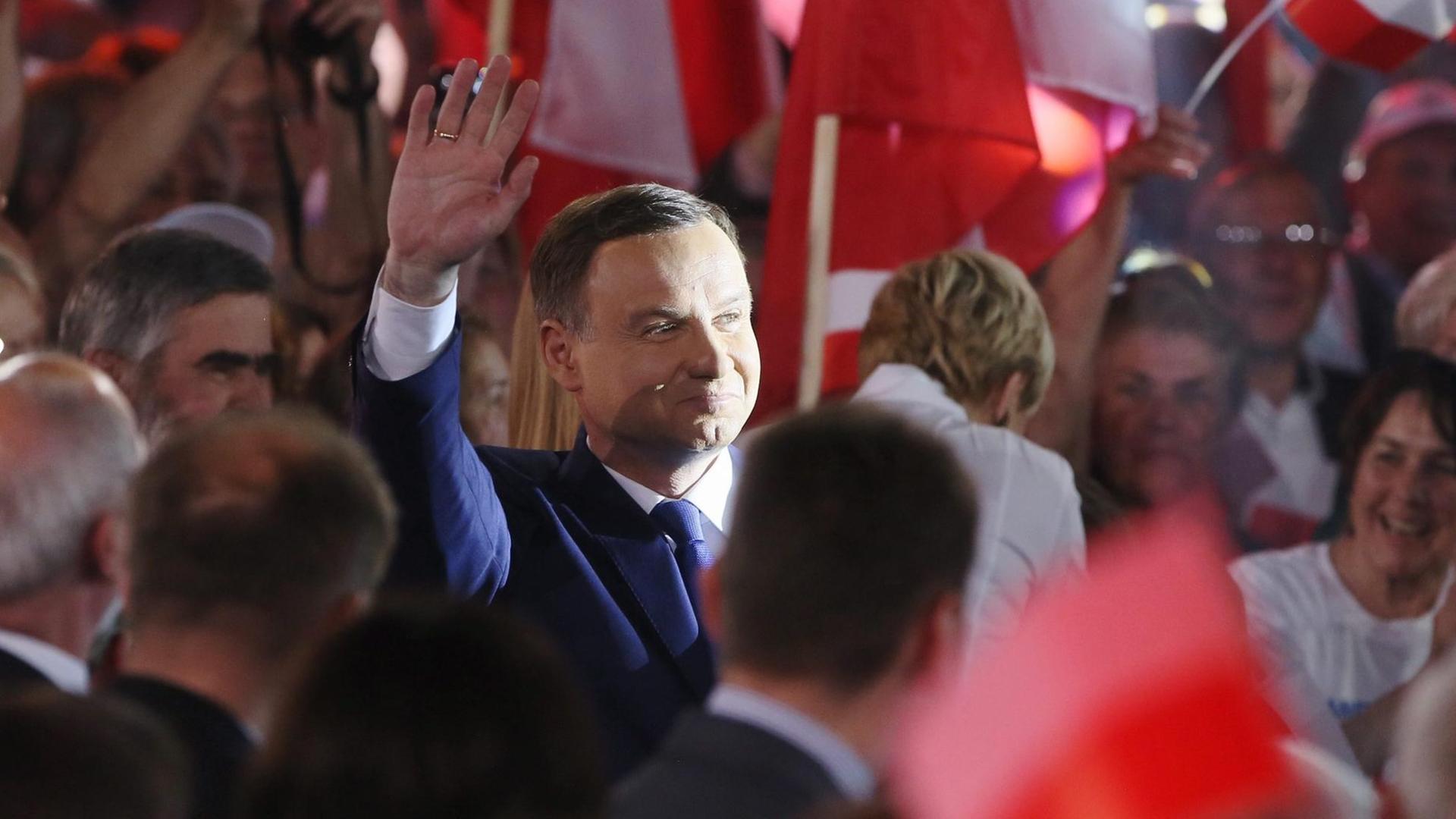 Andrzej Duda winkt, um ihn herum stehen seine Anhänger. Andrzej Duda winkt, um ihn herum stehen seine Anhänger.