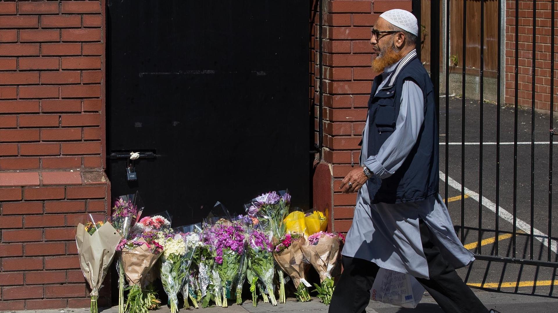 Ein Mann geht am 19.06.2017 in London, Großbritannien, im Stadtteil Finsbury Park an Blumensträußen vorbei. Diese wurden zum Gedenken an den Anschlag dorthin gelegt.