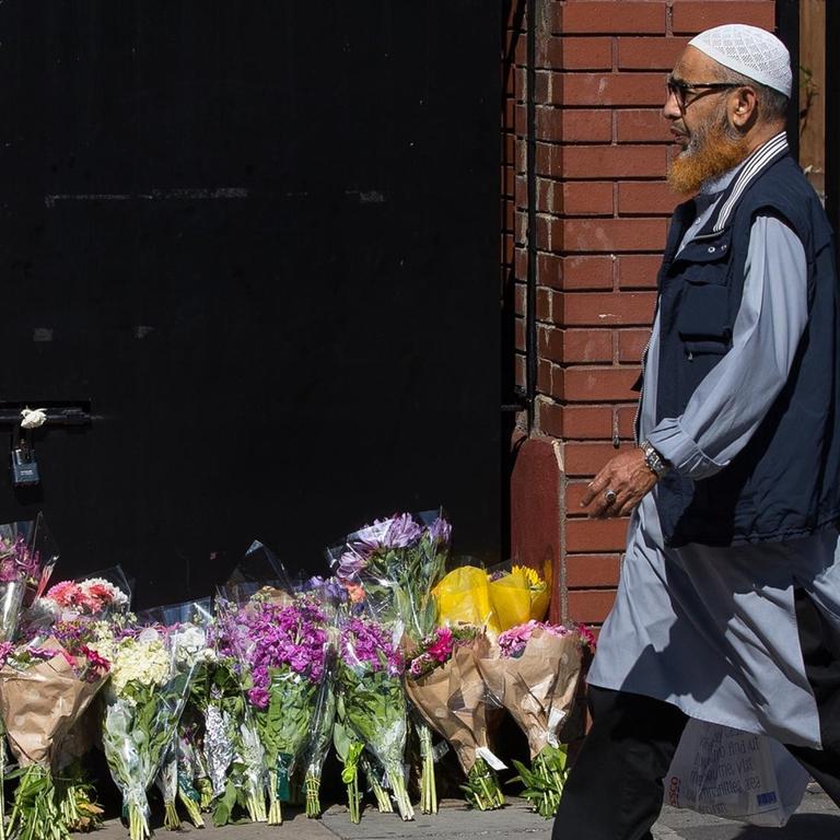 Ein Mann geht am 19.06.2017 in London, Großbritannien, im Stadtteil Finsbury Park an Blumensträußen vorbei. Diese wurden zum Gedenken an den Anschlag dorthin gelegt.