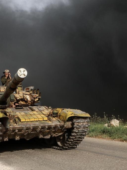 Syrien, Kafr Nabudah: Syrische Oppositionskämpfer fahren auf einer Straße mit einem Panzer an die Front in der Provinz Hama.