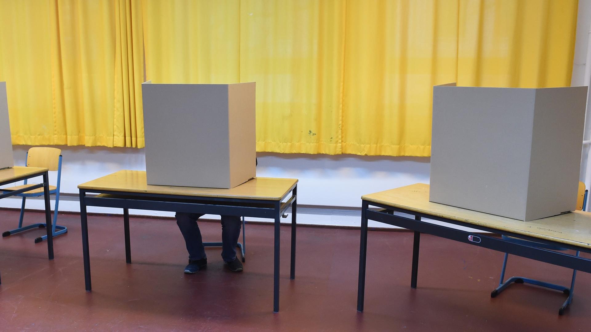 Ein Wähler sitzt am 15.02.2015 in einem Wahllokal in Hamburg und füllt den Stimmzettel für die Bürgerschaftswahl aus.