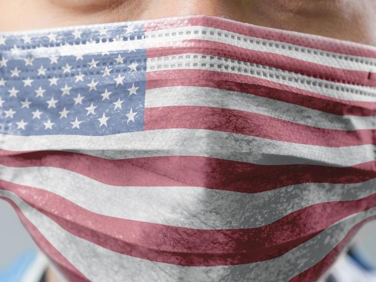 Ein Mensch trägt eine Maske, die mit der Flagge der USA bedruckt ist.