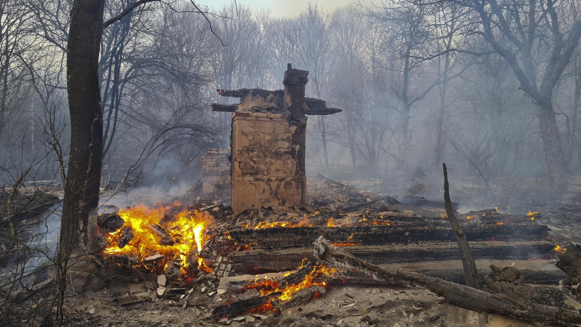 Ein Rest von einem Haus im Wald bei Tschernobyl brennt.
