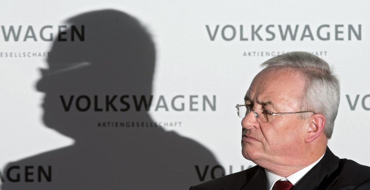 September 2015: VW-Chef Martin Winterkorn schaut zerknirscht vor einem Volkswagen-Schriftzug. Neben ihm sein Schatten.