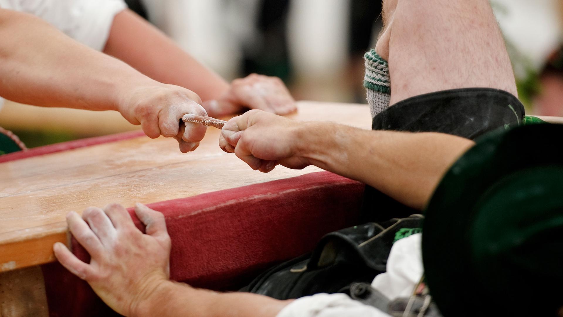 Teilnehmer kämpfen am in Garmisch-Partenkirchen (Oberbayern) um die Deutsche Meisterschaft im Fingerhakeln. Die Gegner sitzen sich bei dem Wettbewerb auf Hockern an einem Tisch gegenüber und versuchen, den Gegner am Finger zu sich herüberzuziehen. Hinter jedem Hakler sitzt ein Auffänger.