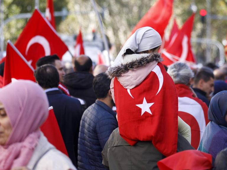 Menschen schwenken in der Öffentlichkeit türkische Staatsflaggen.