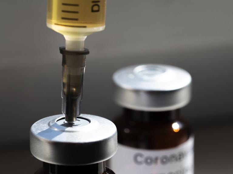 Eine Spritze steckt in einem Fläschchen mit der Aufschrift "Coronavirus-Impfstoff" und