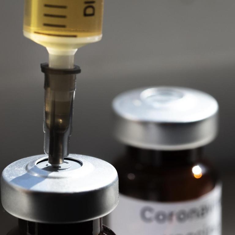 Eine Spritze steckt in einem Fläschchen mit der Aufschrift "Coronavirus-Impfstoff" und 