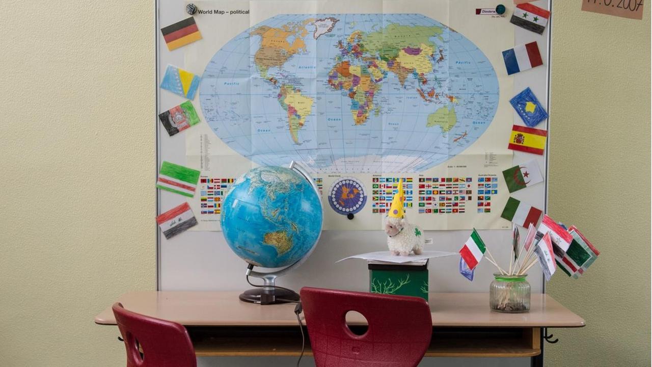 Eine Schulbank mit einem Globus, im Hintergrund eine Weltkarte