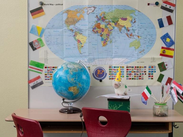 Eine Schulbank mit einem Globus, im Hintergrund eine Weltkarte.