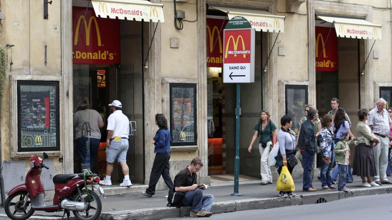 Passanten stehen vor einer Filiale der amerikanischen Fast-Food-Kette McDonald's in Rom.