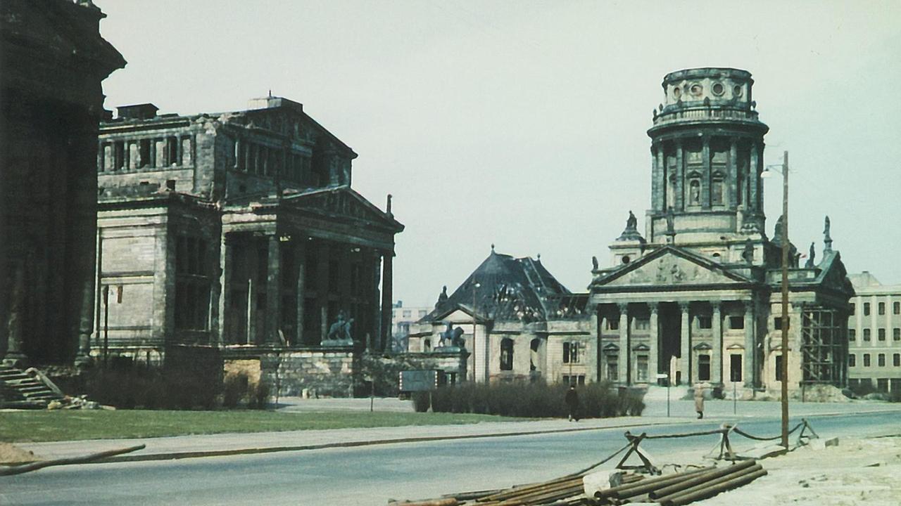 Auf dem fast menschenleeren Berliner Gendarmenmarkt stehen zerstörte, zum Teil schwarze Gebäudeteile, die den Schinkelbau und den französischen Dom erkennen lassen.