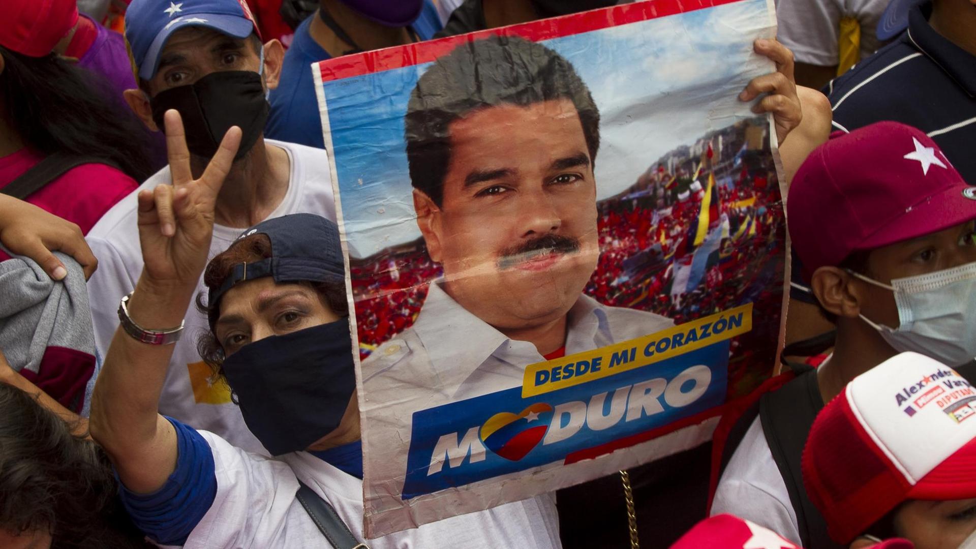 Eine Unterstützerin des venezolanischen Präsidenten Maduro hält während einer Abschlusskundgebung ein Schild mit seinem Gesicht darauf. Am 6. Dezember soll eine umstrittene Parlamentswahl in dem politisch tief gespaltenen südamerikanischen Land stattfinden. Große Teile der Opposition befürchten Wahlbetrug und wollen die Abstimmung deshalb boykottieren.