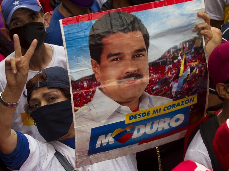 Eine Unterstützerin des venezolanischen Präsidenten Maduro hält während einer Abschlusskundgebung ein Schild mit seinem Gesicht darauf. Am 6. Dezember soll eine umstrittene Parlamentswahl in dem politisch tief gespaltenen südamerikanischen Land stattfinden. Große Teile der Opposition befürchten Wahlbetrug und wollen die Abstimmung deshalb boykottieren.