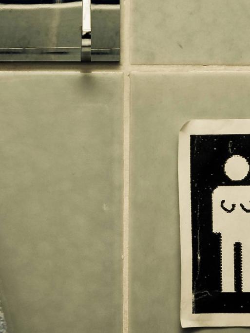 Unisex Handtuch. Symbole auf einem Schild: Für Männer und Frauen. Jemand hat signifikante Körpermerkmale für Transgender People ergänzt.